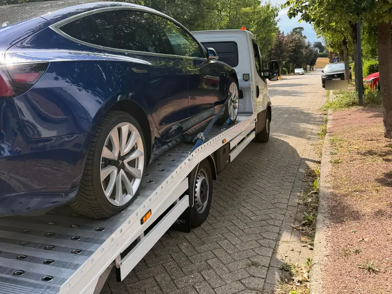 Tesla Model 3 sanglée sur le plateau de la dépanneuse, roues levées