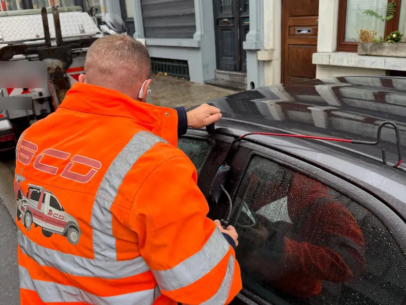 Dépanneur BCD en veste orange qui ouvre la portière d'une voiture verrouillée avec un coussin gonflable